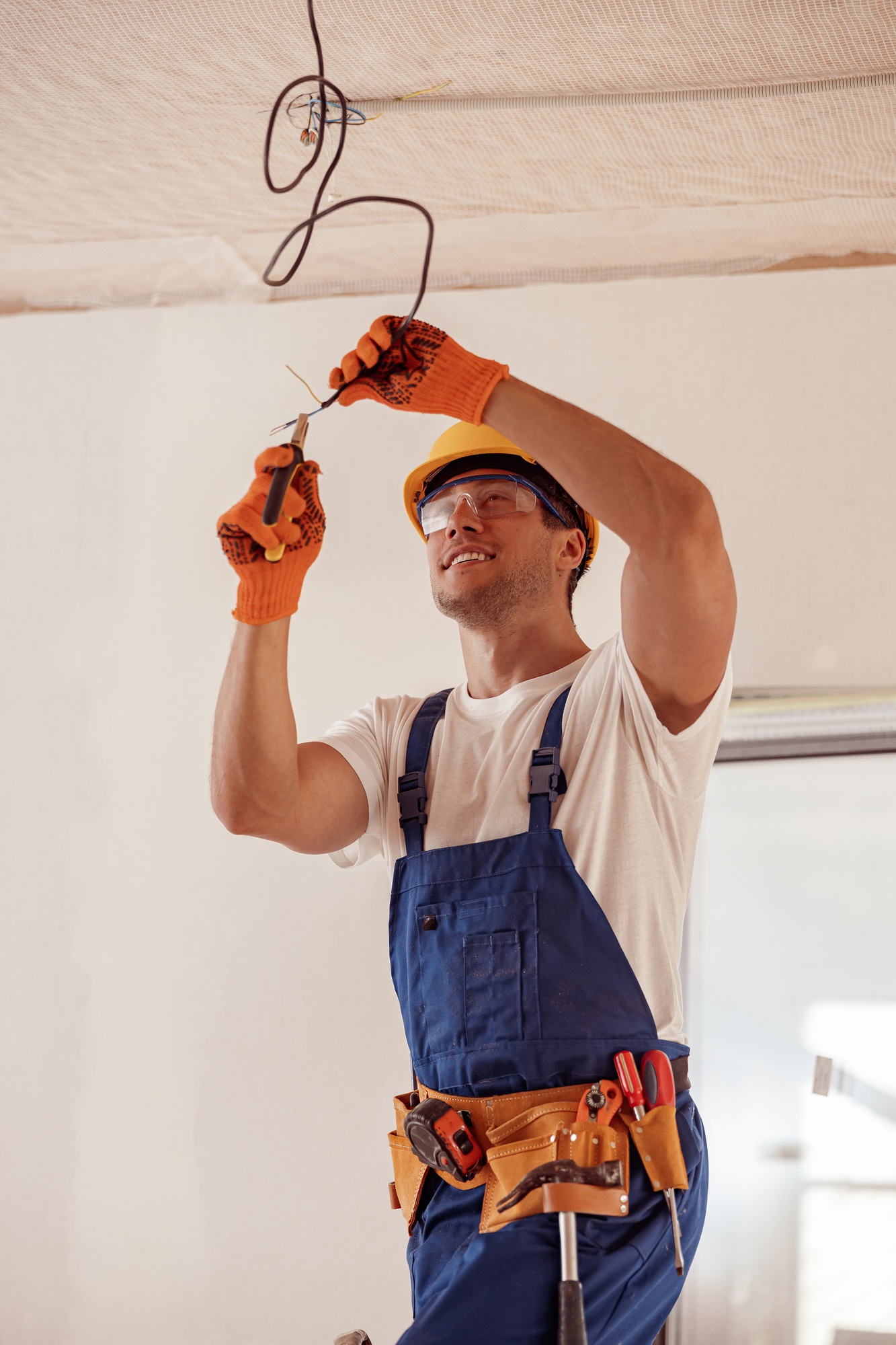 Electrician repairing an electric cable on a ceiling