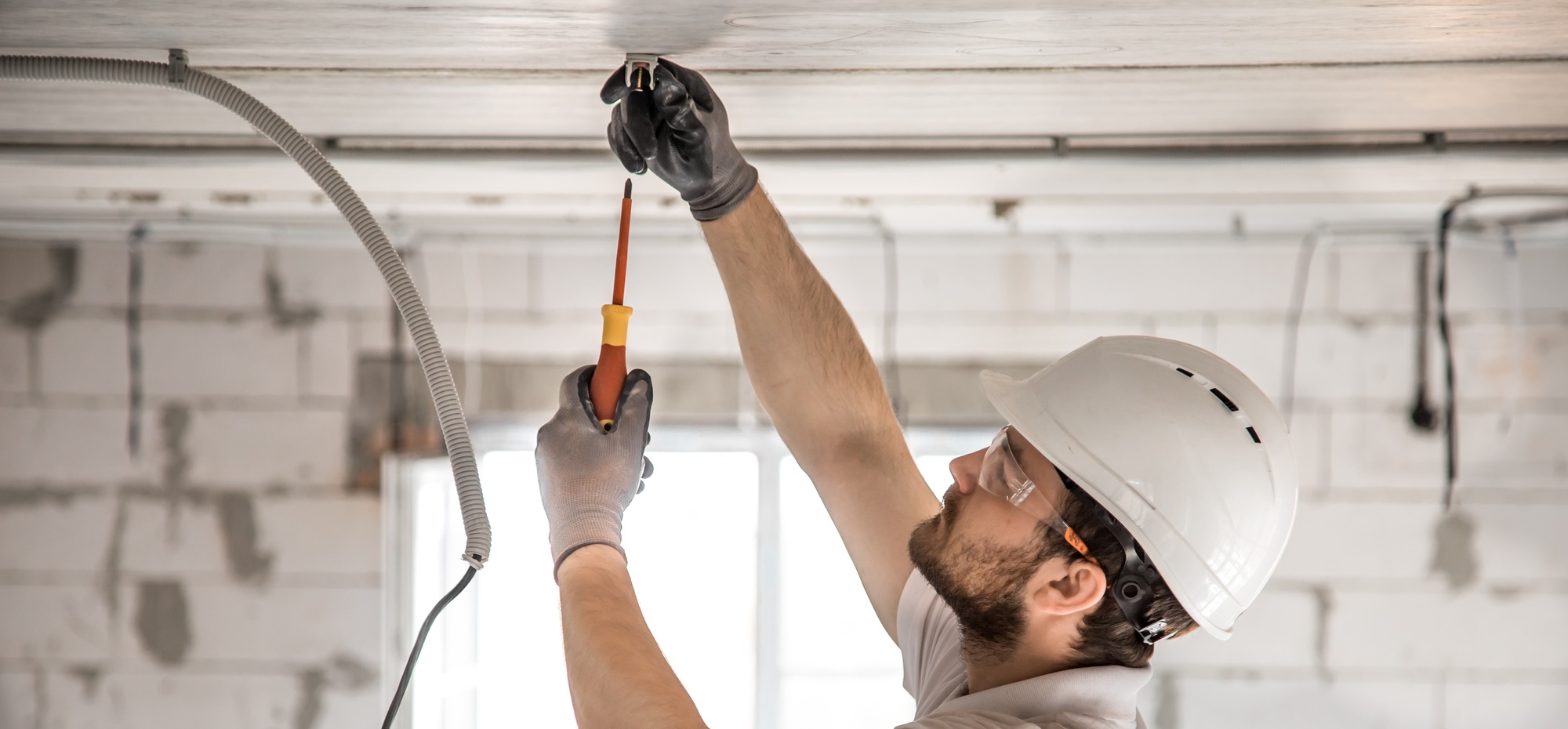 Electrician installer with a tool in his hands working with cable on the construction site